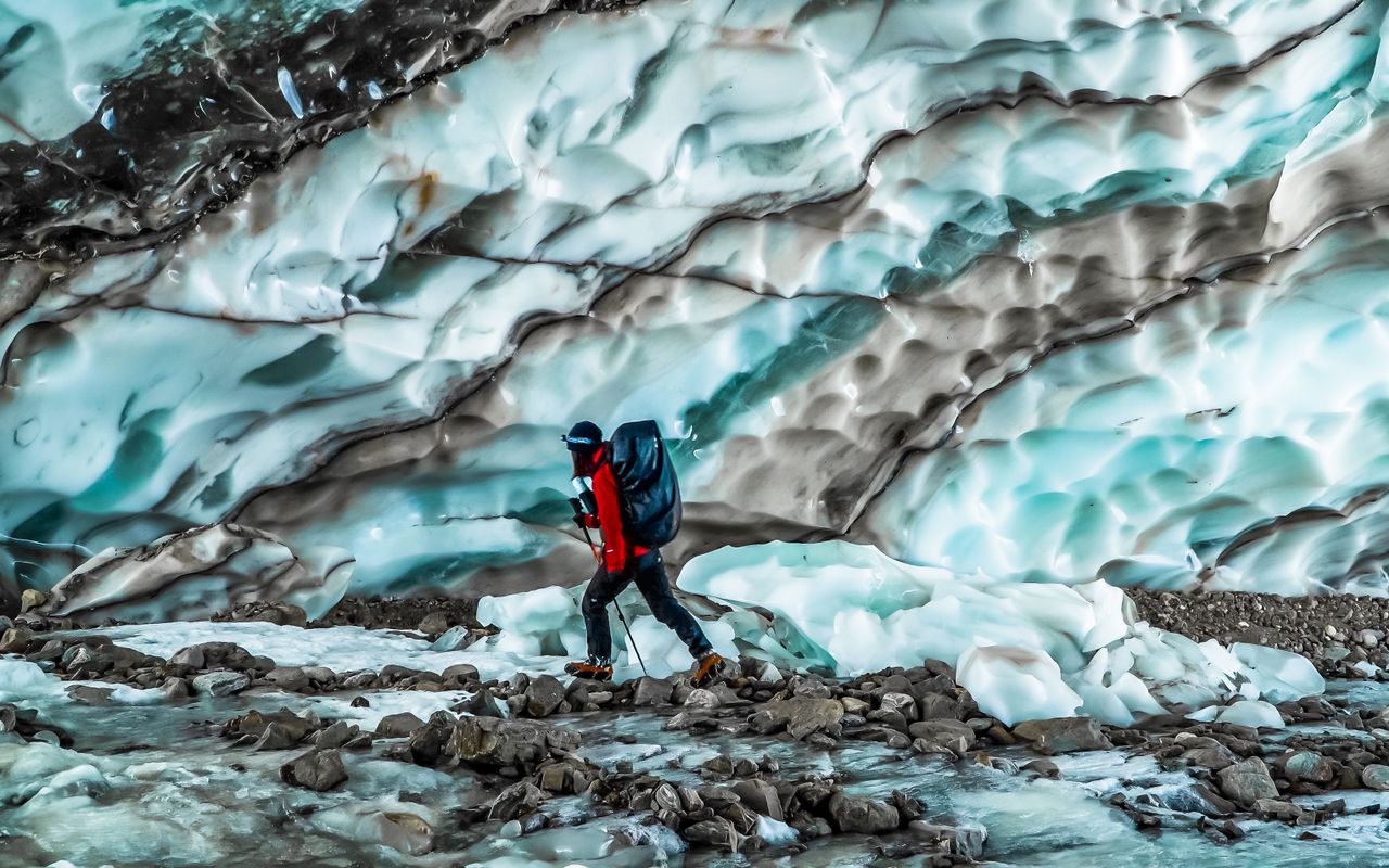 A lone hiker treks through a stunning glacier landscape in Yunnan, China, capturing natures beauty.