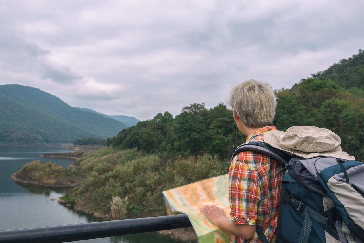 Traveler with backpack and map exploring picturesque mountain landscape.