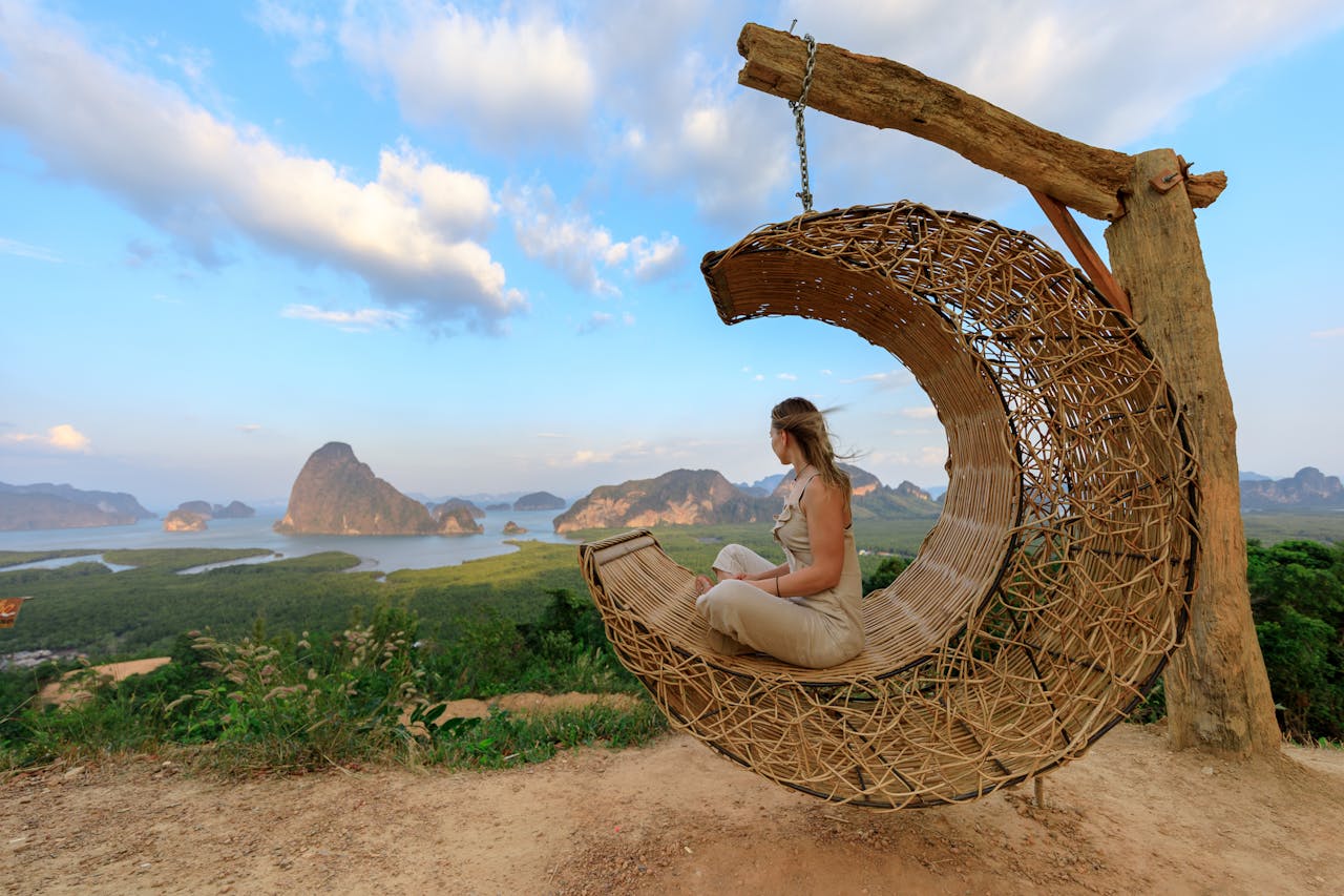 Woman in rattan hammock enjoying Phang-nga Bays scenic view at sunset.